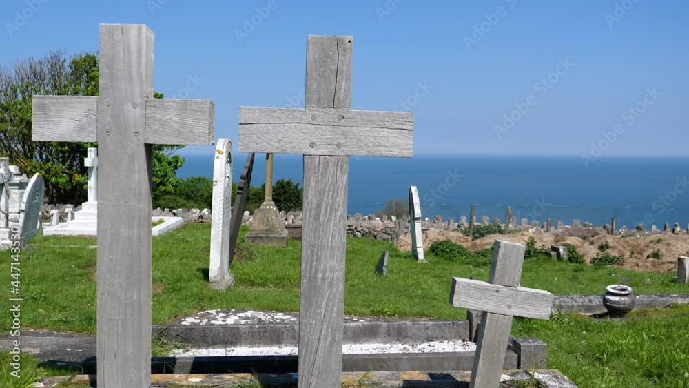 Static shot of family grave with three wooden crosses in seaside cemetery, light breeze moving tree branches and grass. Static shot of family grave with three wooden crosses in seaside cemetery, light breeze moving tree branches and grass.