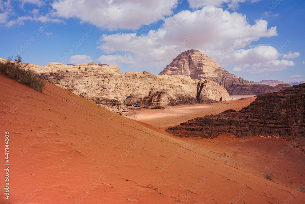 view of red relief mountains from a sand dune, blue sky with beautiful white clouds, Wadi Rum desert, nature of Jordan view of red relief mountains from a sand dune, blue sky with beautiful white clouds, Wadi Rum desert, nature of Jordan