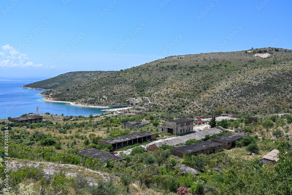 Alte Militärstation mit einem U-Boot-Bunker im Berg in Porto Palermo in Albanien, Küstenlinie mit Meer und blauem Himmel im Sommer