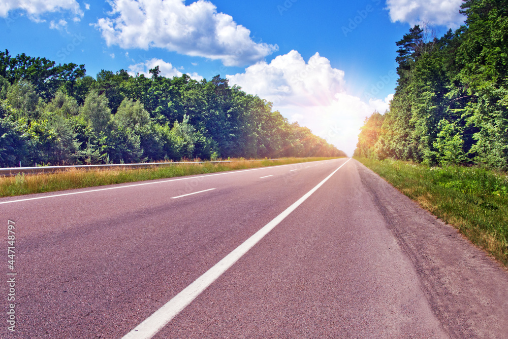 Highway leading to the sun among the trees in summer Highway leading to the sun among the trees in summer