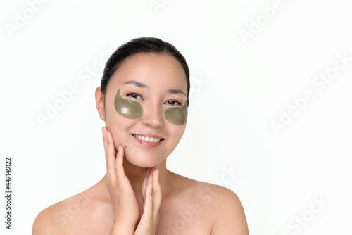 a young attractive Asian woman with patches under her eyes on a white isolated background. the concept of skin care, prevention of wrinkles