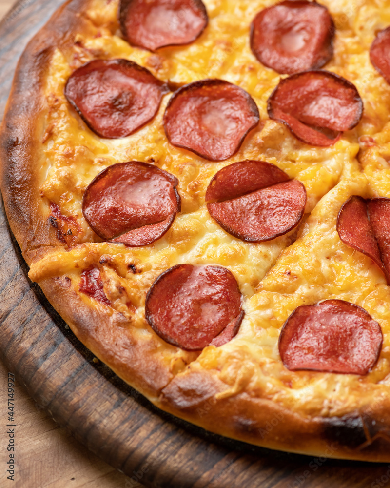 Pepperoni pizza with salami sausage, melted cheese and golden crispy crust. Close-up shot. Food background or texture. Soft Focus. Vertical format. Pepperoni pizza with salami sausage, melted cheese and golden crispy crust. Close-up shot. Food background or texture. Soft Focus. Vertical format.