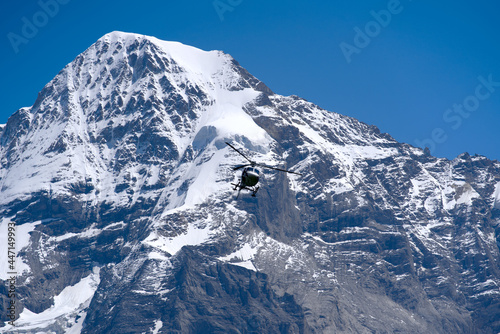 Peak Mönch (Monk) at Bernese highland on a sunny summer day with blue sky background and transport helicopter in the center. Photo taken July 20th, 2021, Lauterbrunnen, Switzerland.