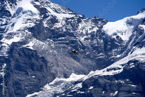 White transport helicopter at Lauterbrunnen on a sunny summer day with swiss alps in the background. Photo taken July 20th, 2021, Lauterbrunnen, Switzerland.