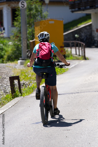 Fototapeta Naklejka Na Ścianę i Meble -  Middle aged woman on mountain bike in the Swiss alps on a beautiful summer day. Photo taken July 20th, 2021, Lauterbrunnen, Switzerland.
