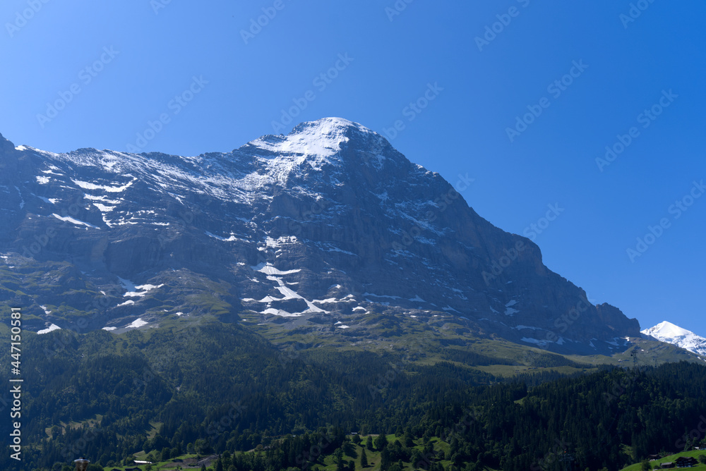 Mountain peak Eiger at Bernese highland on a sunny summer day with blue sky background and clouds in the foreground. Photo taken July 20th, 2021, Lauterbrunnen, Switzerland.