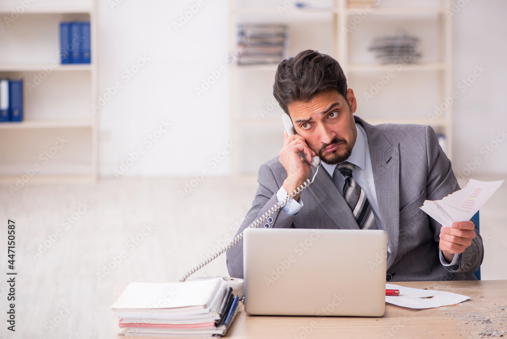 Young male employee unhappy with excessive work in the office Young male employee unhappy with excessive work in the office