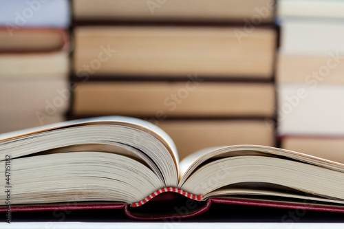 An Opened Book With Stack Of Books On The Background