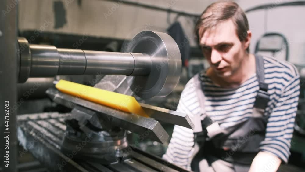 Front view. A worker in production processes a polyurethane part on a horizontal milling machine. A milling cutter at a polyurethane products manufacturing plant makes an order according to drawings Front view. A worker in production processes a polyurethane part on a horizontal milling machine. A milling cutter at a polyurethane products manufacturing plant makes an order according to drawings