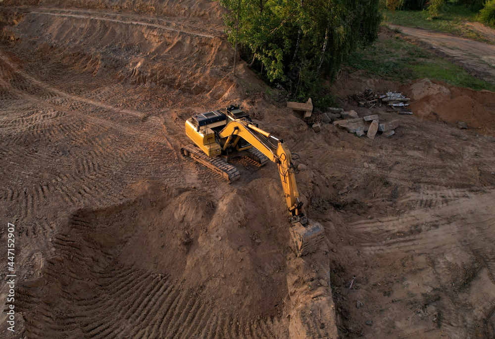 Excavator dig ground at construction site. Foundation pit for a multi-story building. Earth-moving heavy equipment. Arial view of the Digger on earthworks. Trench for laying external sewer pipes. Excavator dig ground at construction site. Foundation pit for a multi-story building. Earth-moving heavy equipment. Arial view of the Digger on earthworks. Trench for laying external sewer pipes.