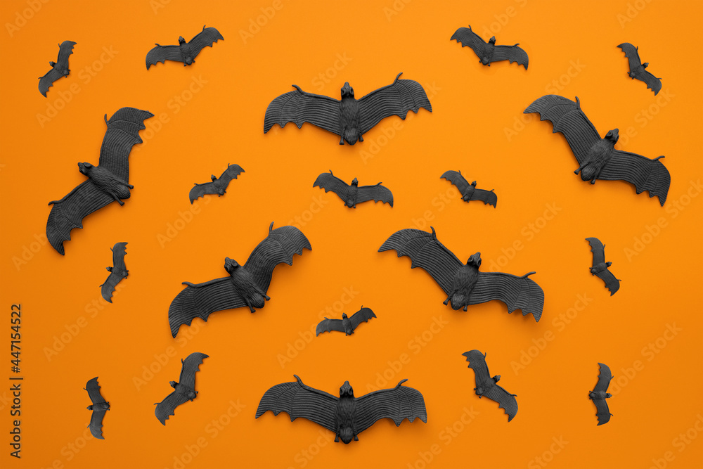A lot of black bats flying on an orange background. Scary halloween flat lay composition on an orange background. Halloween decoration concept A lot of black bats flying on an orange background. Scary halloween flat lay composition on an orange background. Halloween decoration concept