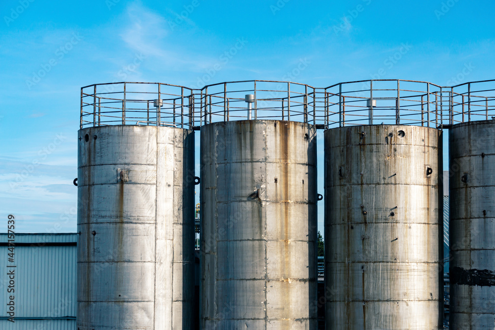 old metal industrial silo towers for bulk and liquid materials against the sky old metal industrial silo towers for bulk and liquid materials against the sky