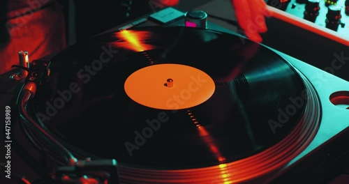 Deejay spinning vinyl musical record on turntable during dj rave, close-up. Nightlife and music