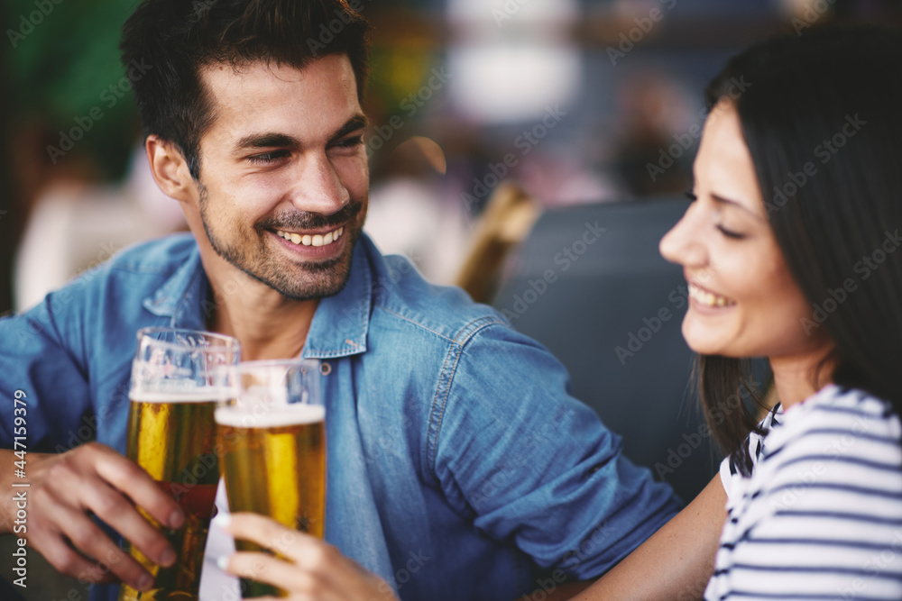 Young couple at a summer bar toast with beer