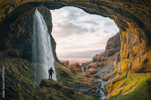 Adventurous young man standing behind waterfall in the highlands of Iceland. High quality panorama photo. High quality photo