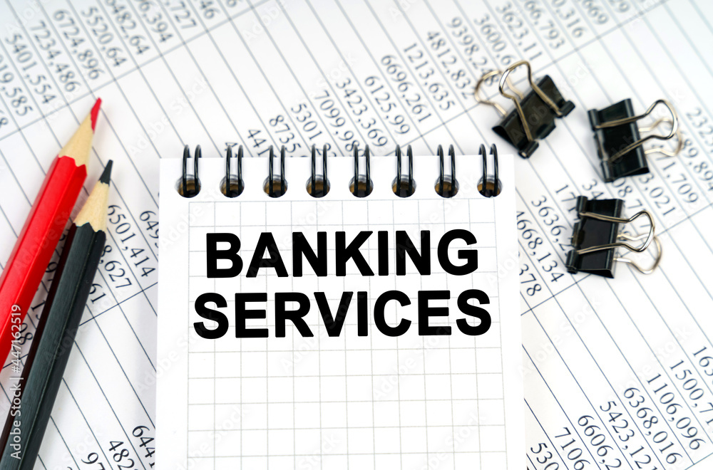 On the table are reports, pencils and a notebook with the inscription - BANKING SERVICES On the table are reports, pencils and a notebook with the inscription - BANKING SERVICES