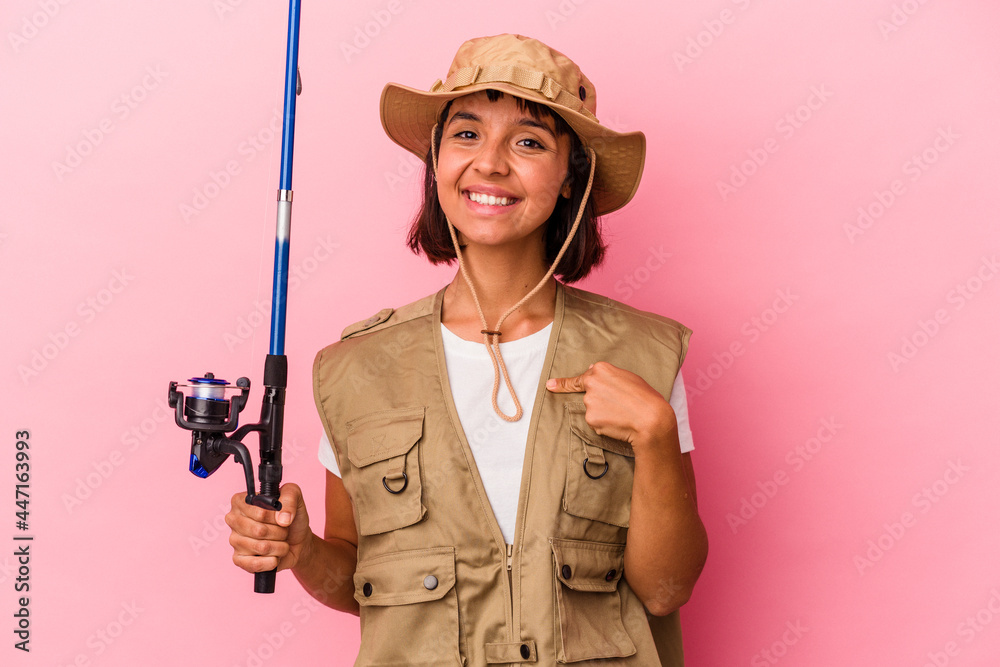 Young mixed race fisherwoman holding a rod isolated on pink background person pointing by hand to a shirt copy space, proud and confident Young mixed race fisherwoman holding a rod isolated on pink background person pointing by hand to a shirt copy space, proud and confident