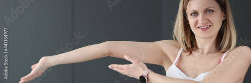 Young smiling woman showing her bent arm photo