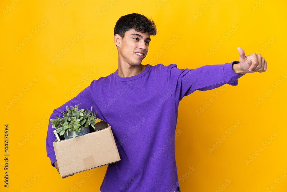 Man making a move while picking up a box full of things giving a thumbs up gesture Man making a move while picking up a box full of things giving a thumbs up gesture