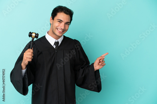 Judge over isolated blue background pointing finger to the side photo