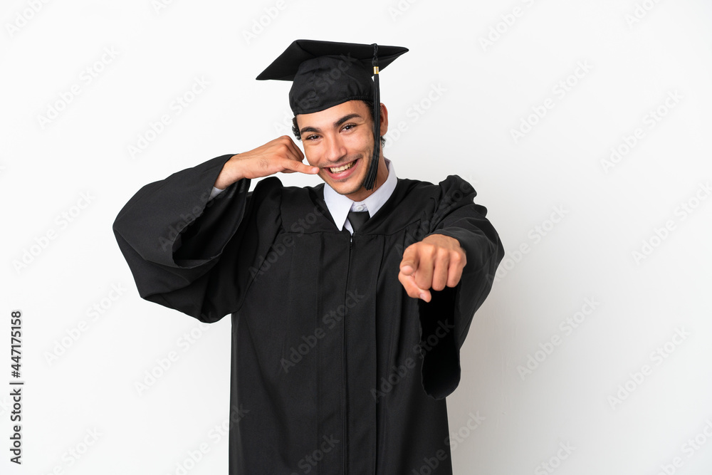 Young university graduate over isolated white background making phone gesture and pointing front Young university graduate over isolated white background making phone gesture and pointing front