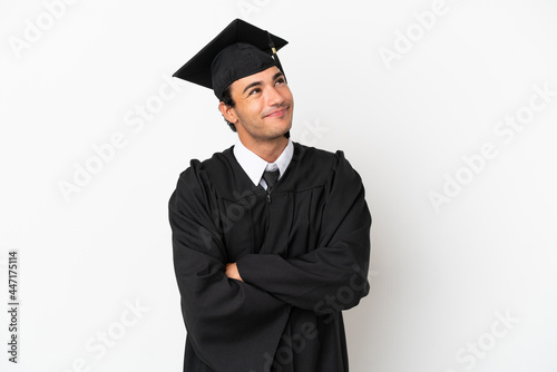 Young university graduate over isolated white background looking up while smiling