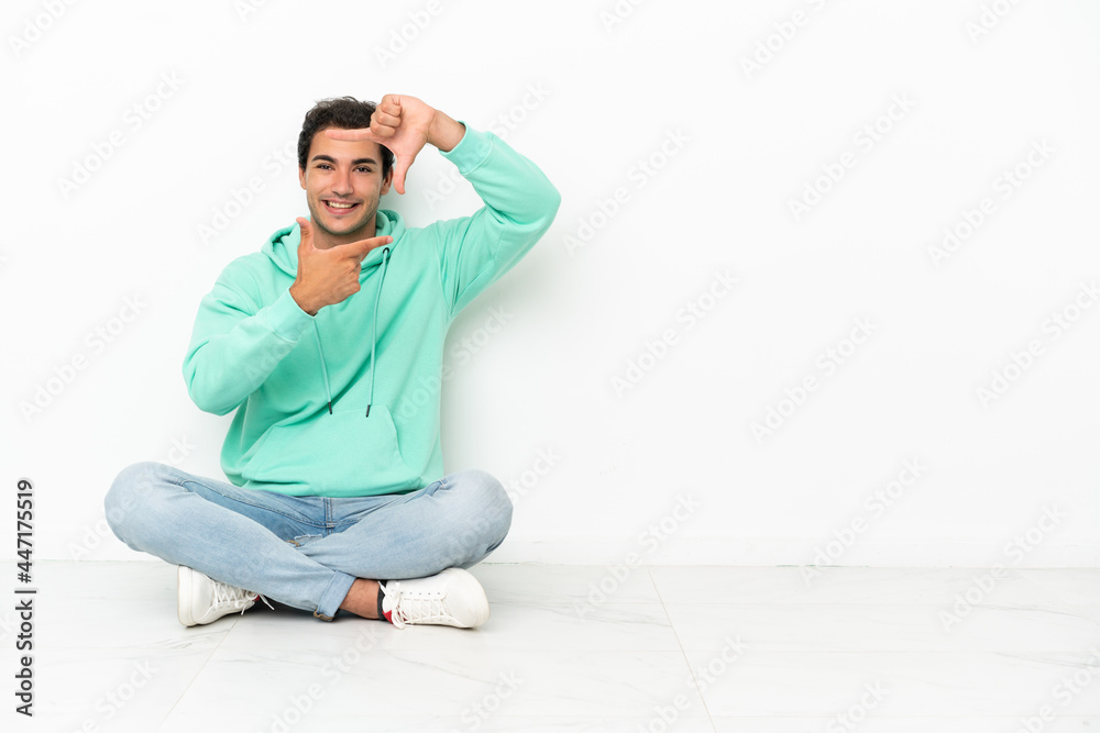 Caucasian handsome man sitting on the floor focusing face. Framing symbol Caucasian handsome man sitting on the floor focusing face. Framing symbol