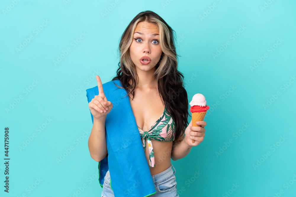 Teenager caucasian girl holding ice cream and towel isolated on blue background intending to realizes the solution while lifting a finger up Teenager caucasian girl holding ice cream and towel isolated on blue background intending to realizes the solution while lifting a finger up