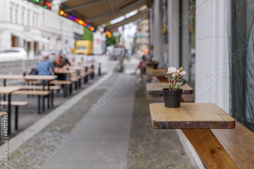 Photography Selective focus at small outdoor wooden table and chair on exterior wall in front of cafe, bar, coffee shop and restaurant on sidewalk in Berlin, Germany