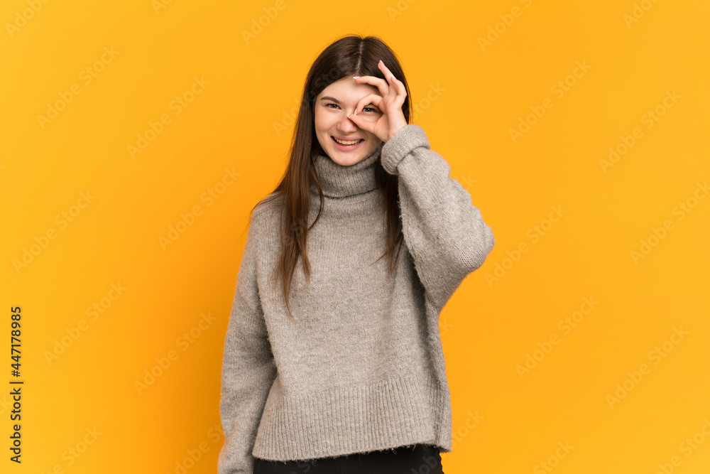 Young Ukrainian girl isolated on yellow background showing ok sign with fingers Young Ukrainian girl isolated on yellow background showing ok sign with fingers