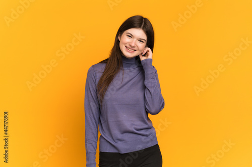 Young Ukrainian girl isolated on yellow background laughing © luismolinero