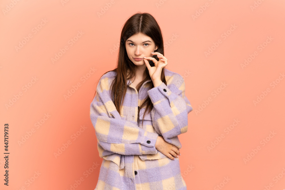 Young Ukrainian girl isolated on pink background showing a sign of silence gesture Young Ukrainian girl isolated on pink background showing a sign of silence gesture