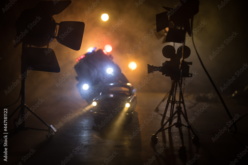 Action movie concept. Police cars and miniature movie set on dark toned background with fog. Police car chasing a car at night. Scene of crime accident.