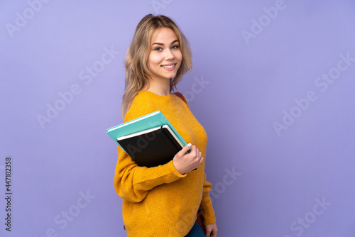 Teenager Russian student girl isolated on purple background with arms crossed and looking forward
