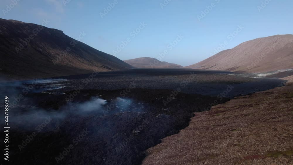 Aerial shot flying over a valley filled with hardened lava in Iceland. Clear blue skies above, some steam rising. Aerial shot flying over a valley filled with hardened lava in Iceland. Clear blue skies above, some steam rising.