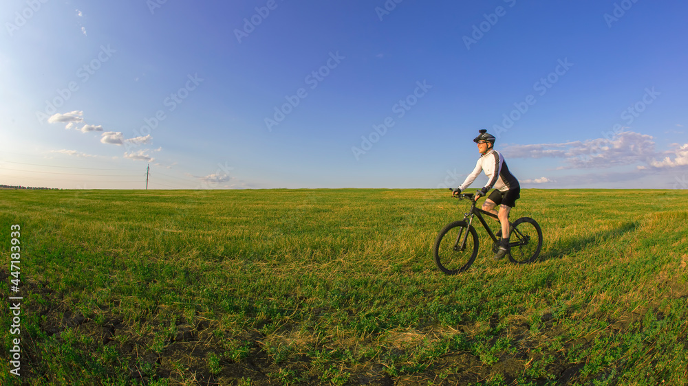 Fototapeta premium The cyclist rides a bicycle on the green grass on the field. Outdoor sports. Healthy lifestyle.