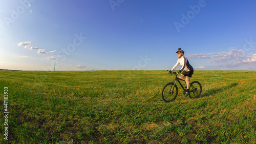 The cyclist rides a bicycle on the green grass on the field. Outdoor sports. Healthy lifestyle.