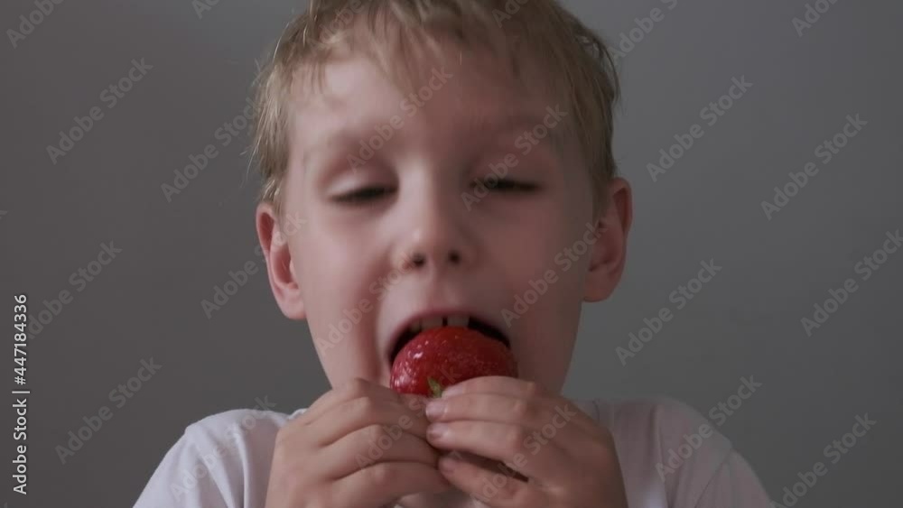 Boy eating strawberries at home. Healthy and Organic Products. Boy eating strawberries at home. Healthy and Organic Products.