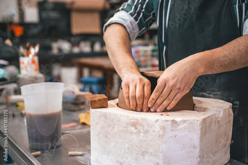 young adult potter molding with clay to make a piece of ceramic