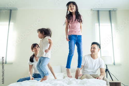 Asian funny family feel happy to spend time together on bed at home. 