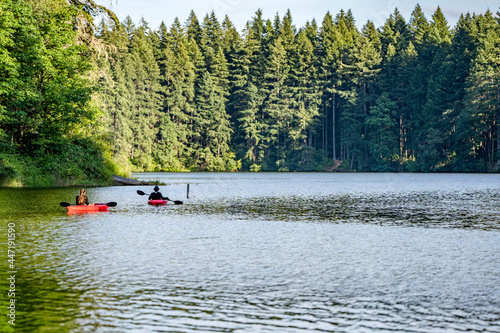Couple of guy and a girl ride on red kayaks on the picturesque Round Lake in Lakamas forest photo