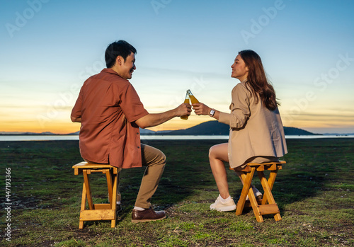 couple in love sitting and party at the grass filed at sunset