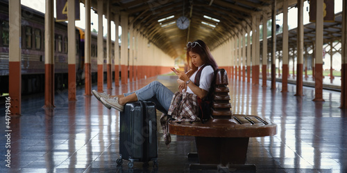 Alone traveler tourist using smartphone with luggage at train station. work and travel lifestyle concept. © itchaznong