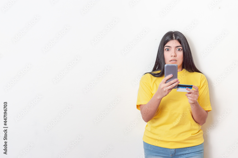 young white latin girl with black hair wearing yellow dress caught making an online transaction with her phone and card young white latin girl with black hair wearing yellow dress caught making an online transaction with her phone and card