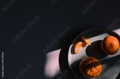 Mandarines in shadows on a pink background.