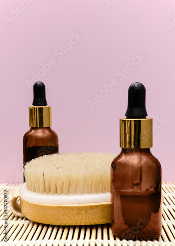 Brown glass bottles with serum, essential oil or other cosmetic product, dry massage brush. Natural organic cosmetics, skin care concept. photo