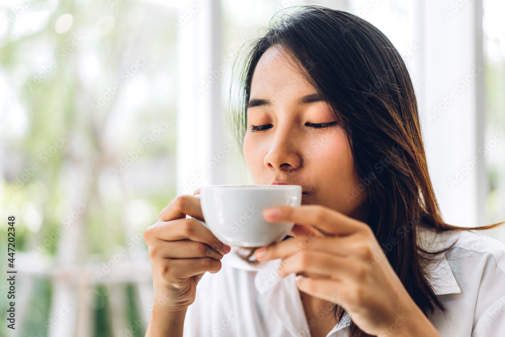 Portrait of smiling happy cheerful beautiful pretty asian woman relaxing drinking and looking at cup of hot coffee or tea.Girl felling enjoy having breakfast in holiday morning vacation on bed at home Portrait of smiling happy cheerful beautiful pretty asian woman relaxing drinking and looking at cup of hot coffee or tea.Girl felling enjoy having breakfast in holiday morning vacation on bed at home