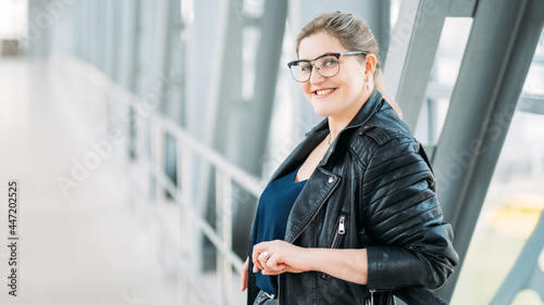 Successful woman lifestyle. Body positive. Female freedom. Urban style. Confident happy satisfied smiling overweight plus size obese model in leather jacket alone on bridge.