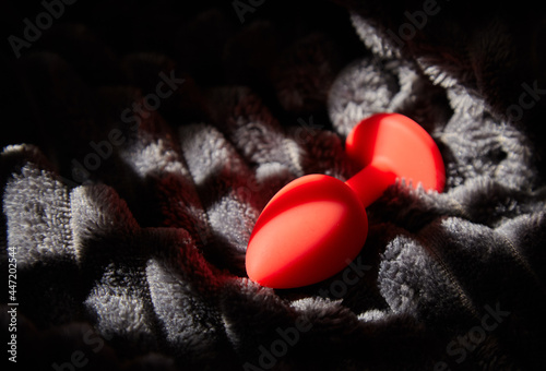 Red anal plug on soft dark blanket