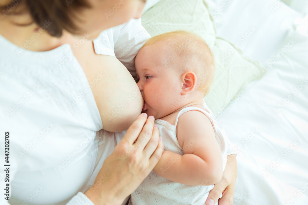 Portrait close-up happy mother feeding breast her baby on white background. Breastfeeding concept, newborn baby boy Portrait close-up happy mother feeding breast her baby on white background. Breastfeeding concept, newborn baby boy